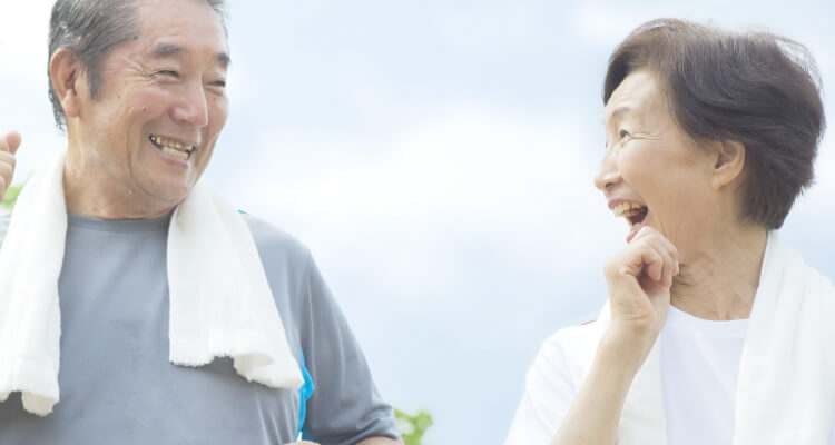 年配の男性と女性が手を振りながら元気に歩いている様子